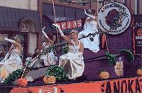A Halloween Parade Float with a Lady in a White Dress Riding It